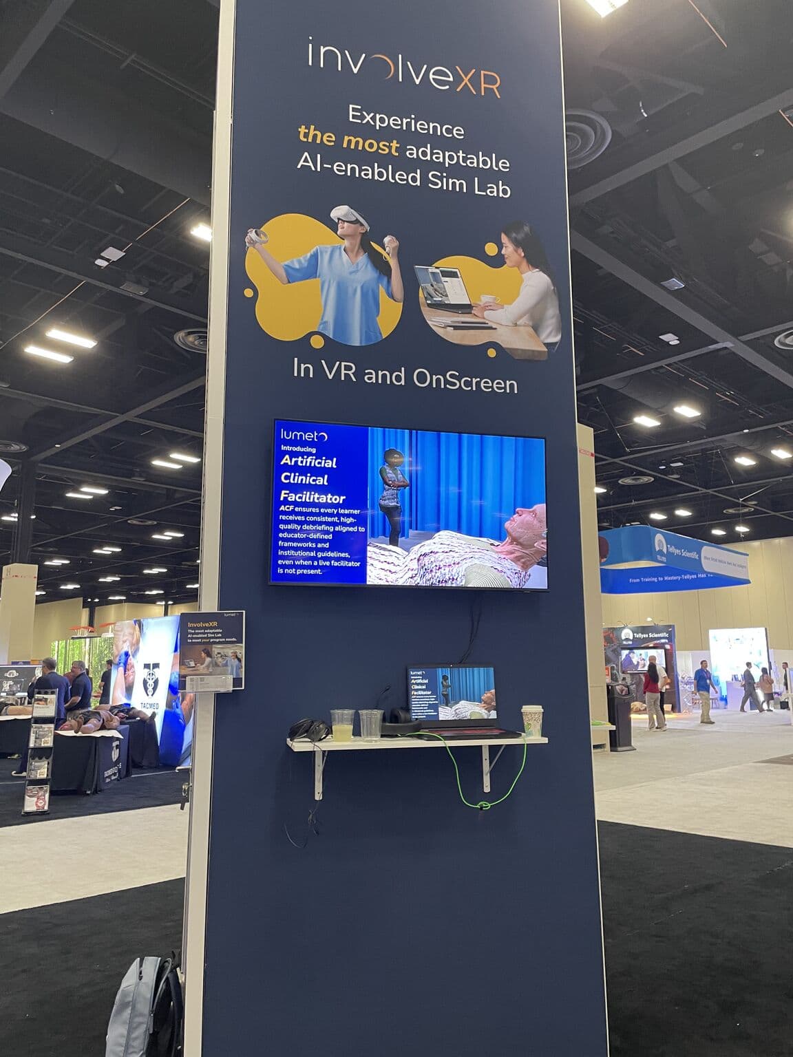 InvolveXR trade-show booth: 'Experience the most adaptable AI-enabled Sim Lab — In VR and OnScreen', with a screen introducing the Artificial Clinical Facilitator