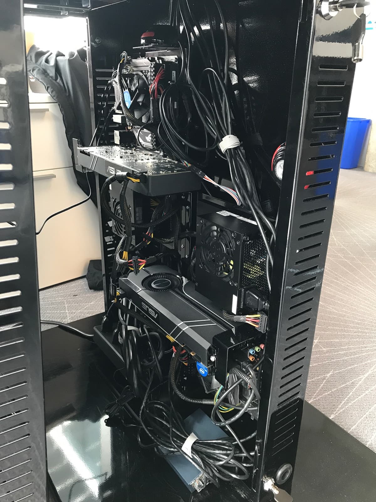 Inside the production kiosk tower: GPU, power supply, motherboard, and cabling mounted vertically behind a vented black panel